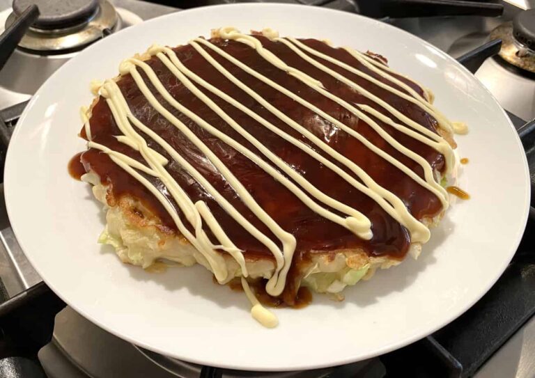 Photo of Okonomiyaki on a plate topped with Okonomiyaki sauce and mayonnaise streaks