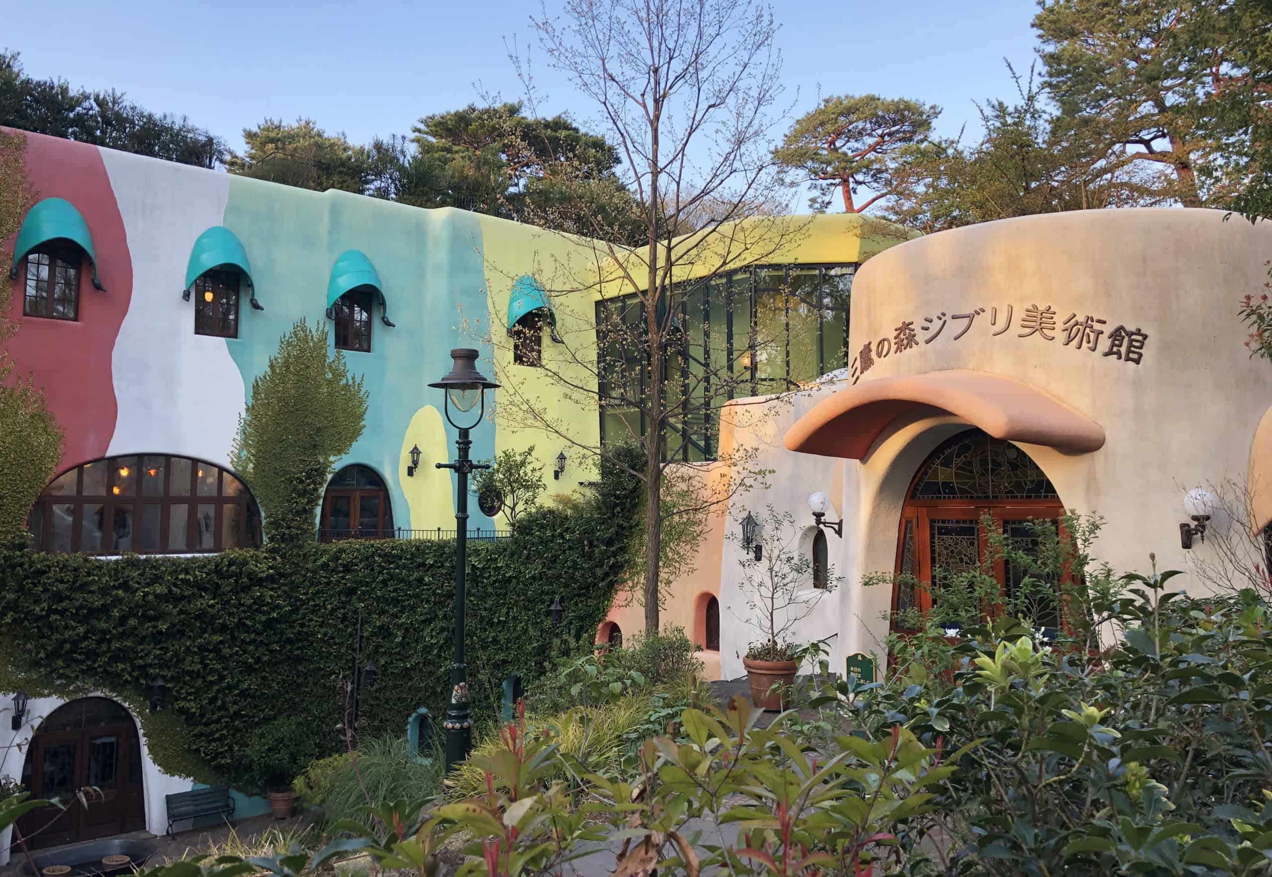 Ghibli Museum building with earth-toned walls, sleek glass façade and arched windows, surrounded by greenery in Mitaka, Japan