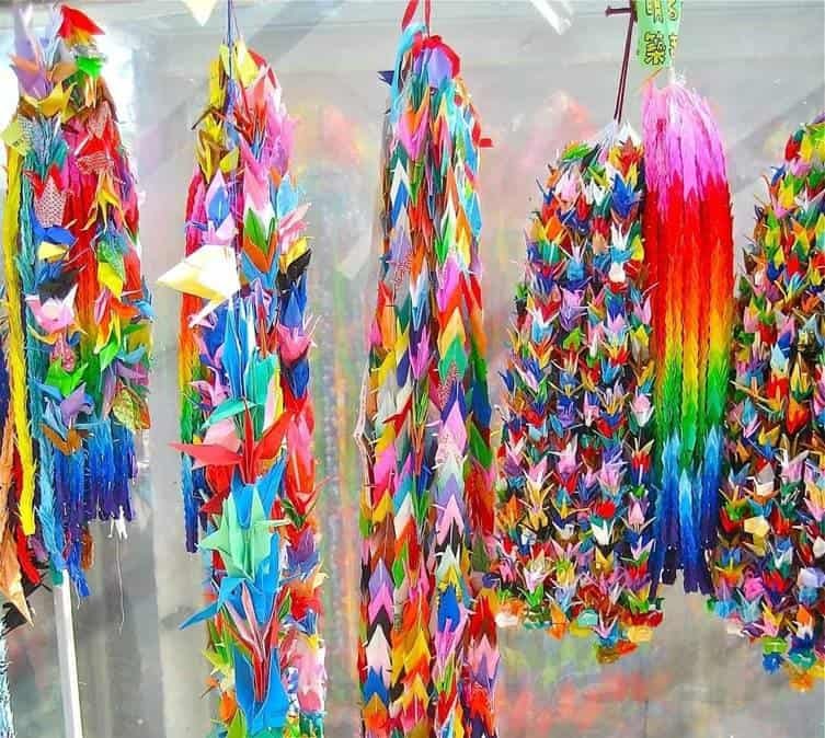Vibrant, multi-colored strings of folded origami paper cranes hanging on display at the Children's Peace Monument in Hiroshima, Japan.