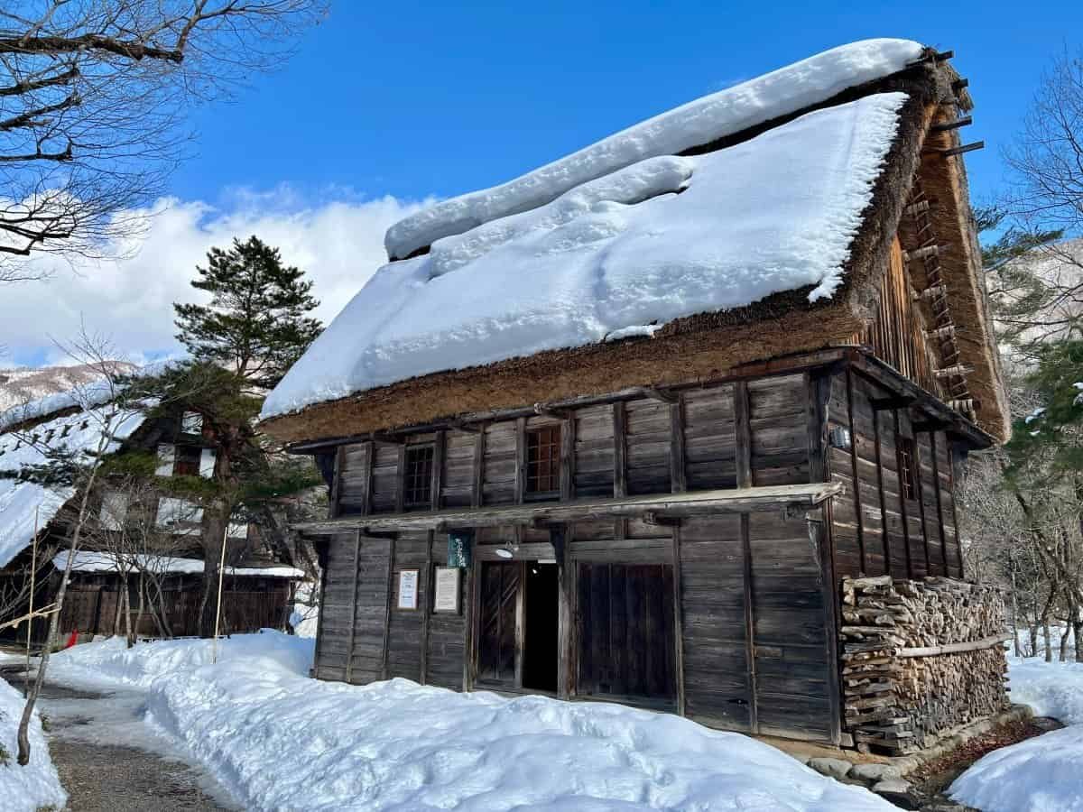 Thick winter snow piled high on a traditional thatched gassho-zukuri house and its roof at the Minka-en open-air museum in Shirakawa-go.