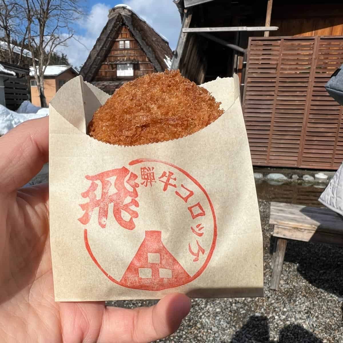 A freshly fried, crispy Hida beef croquette, a popular street food snack in Shirakawa-go.