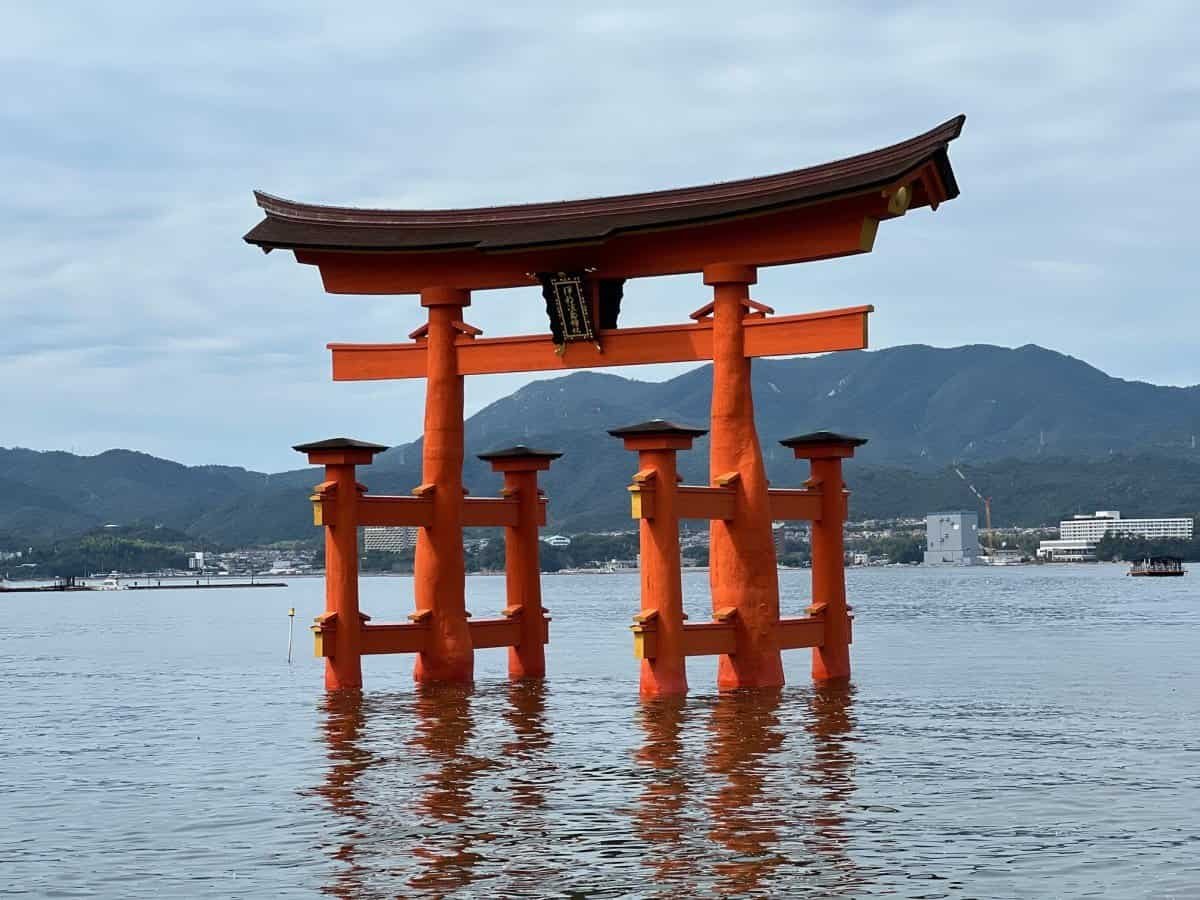 The vermilion O-torii gate of Itsukushima Shrine standing in the water at high tide on Miyajima Island
