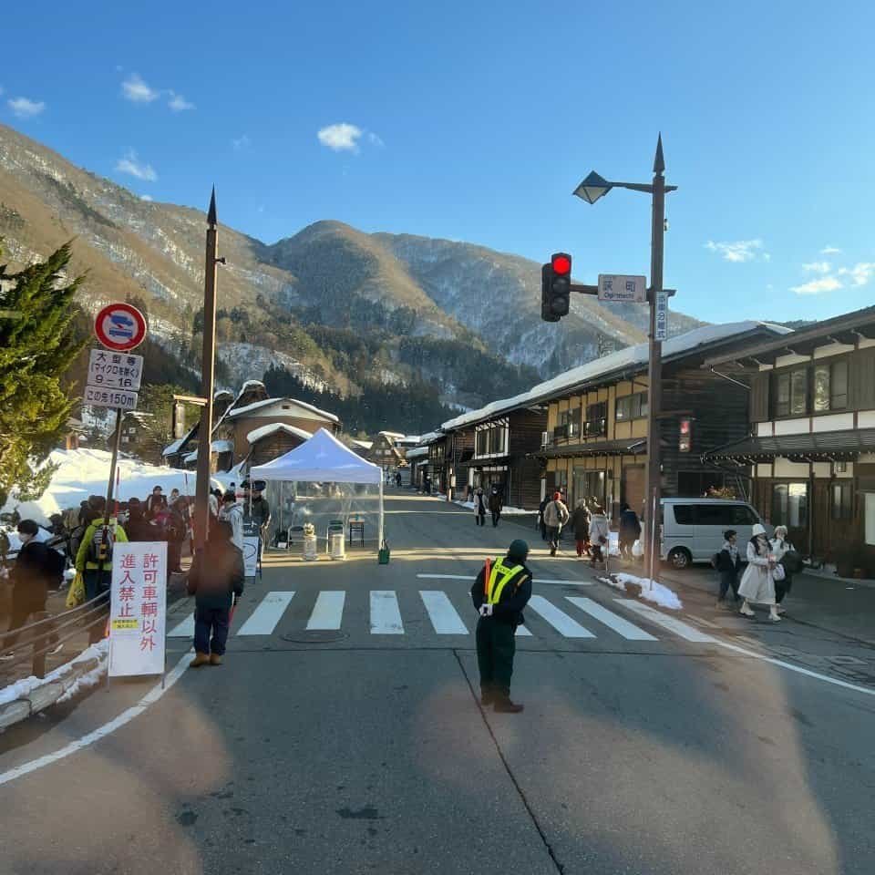 The busy street view near the Ogimachi pedestrian crossing and bus terminal, with travelers who have arrived from Kanazawa to Shirakawago and now heading back in the afternoon.